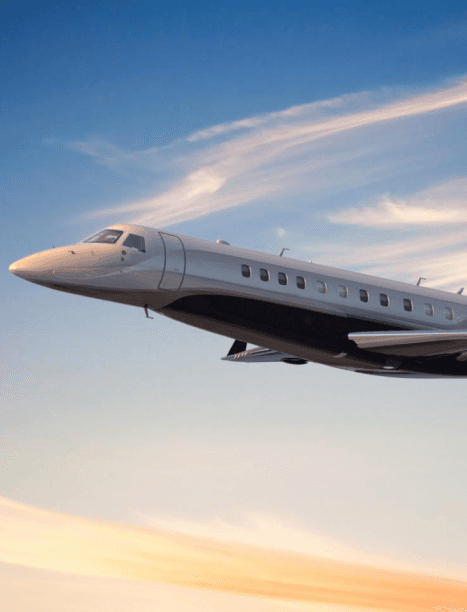 Private jet flying through blue skies at sunset